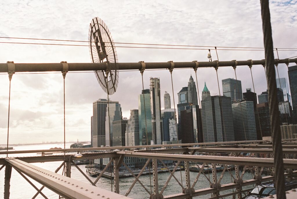 Film photo of the Manhattan skyline seen from the Brooklyn Bridge, featuring bridge cables and industrial details, captured on Kodak Portra 400 film with a Contax G1 camera.