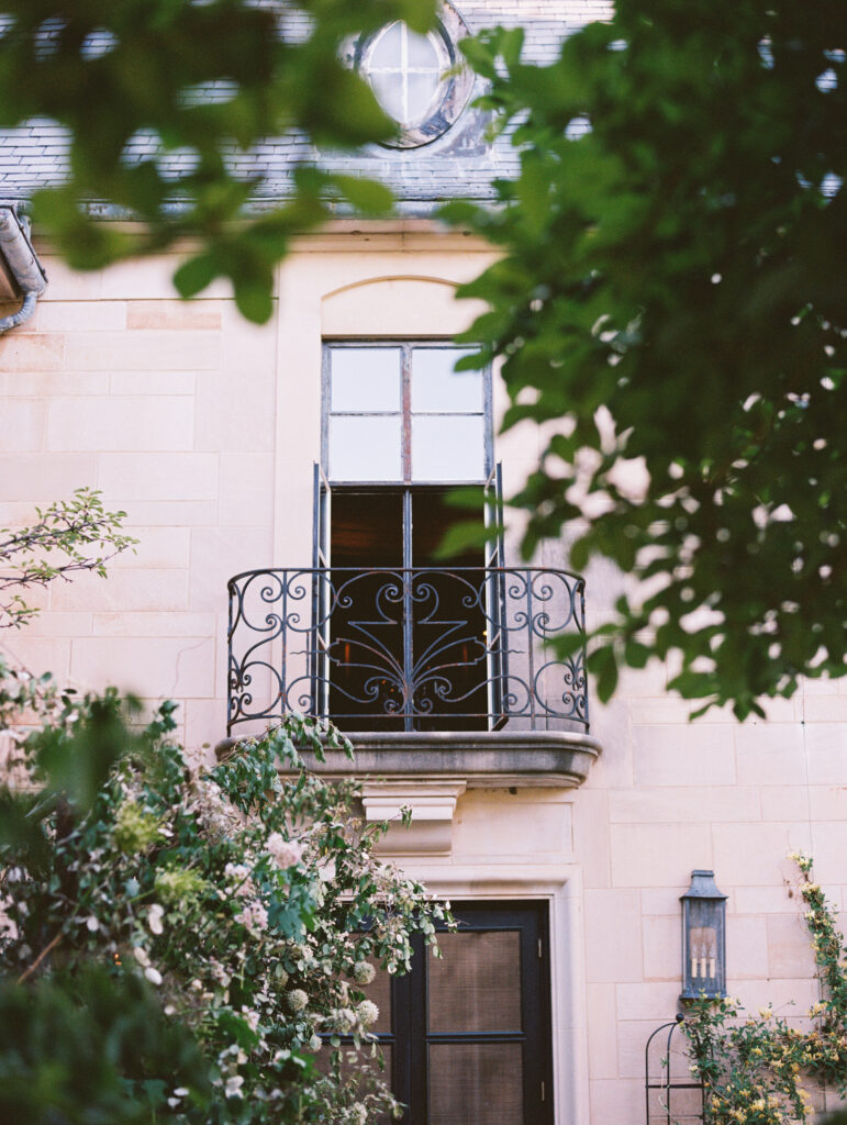 A charming European-style balcony with wrought iron railings, surrounded by lush greenery and delicate floral arrangements, exuding timeless romance.