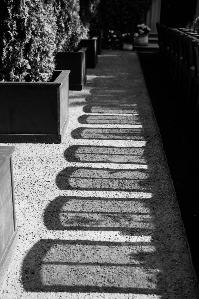 Dramatic shadows from an elegant tablescape cast elongated patterns on the gravel pathway at Greencrest Manor.