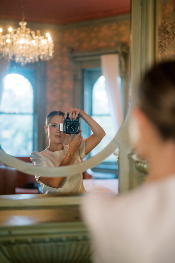 Lexie Vaccaro photographing herself in a vintage mirror, holding a Contax 645 camera in soft, romantic lighting
