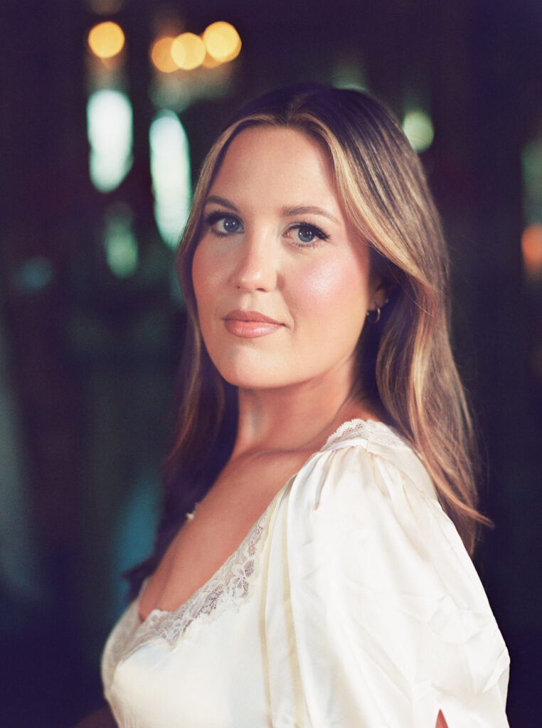 Soft portrait of a woman in a cream dress with lace detailing, glowing in natural light