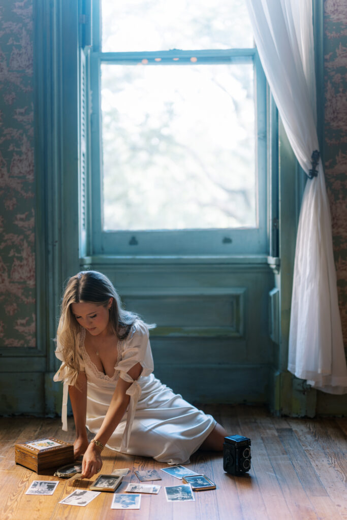 Lexie Vaccaro sorting through heirloom family photographs on wooden floor in vintage-inspired room