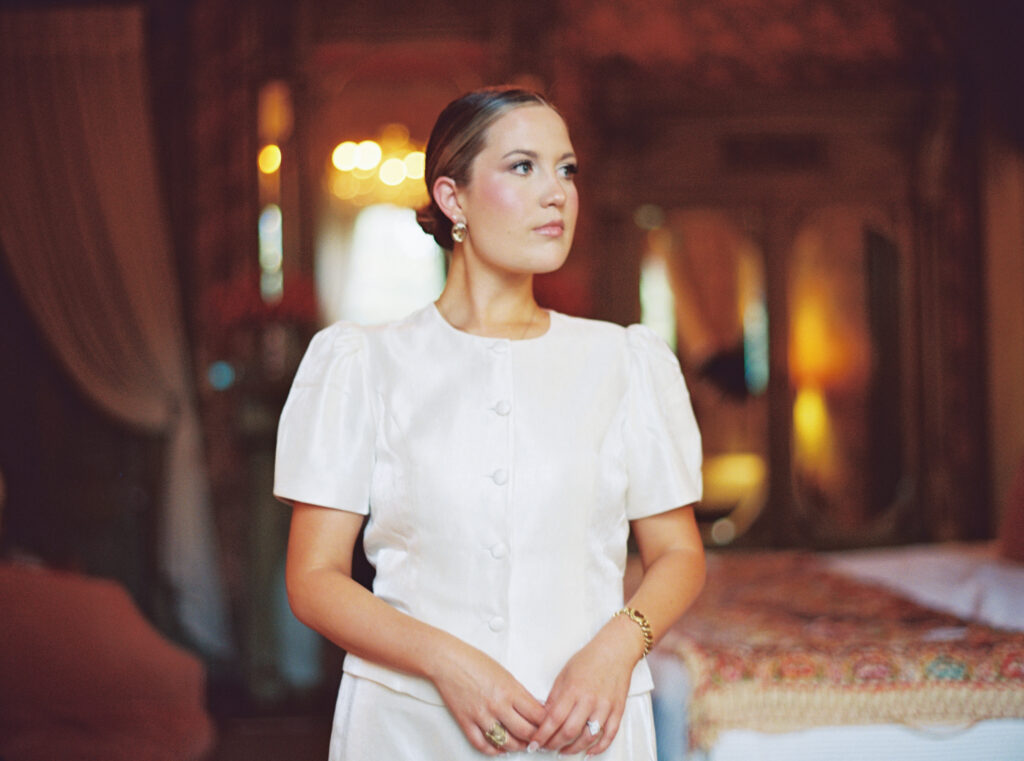 Lexie Vaccaro standing in a vintage bedroom with soft golden lighting, wearing an ivory puff-sleeve set