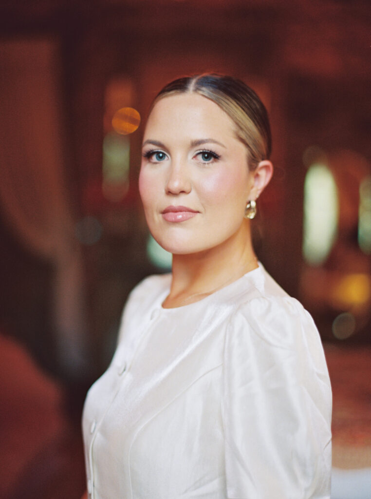 Close-up portrait of Lexie Vaccaro in pearl-toned vintage blouse, softly lit in a warm, romantic setting