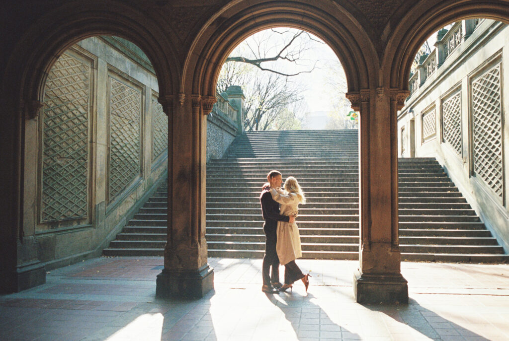 Film photograph of a couple standing beneath the arches at Bethesda Terrace in Central Park, New York City, captured by Lexie Vaccaro Photography during a fall engagement session.

