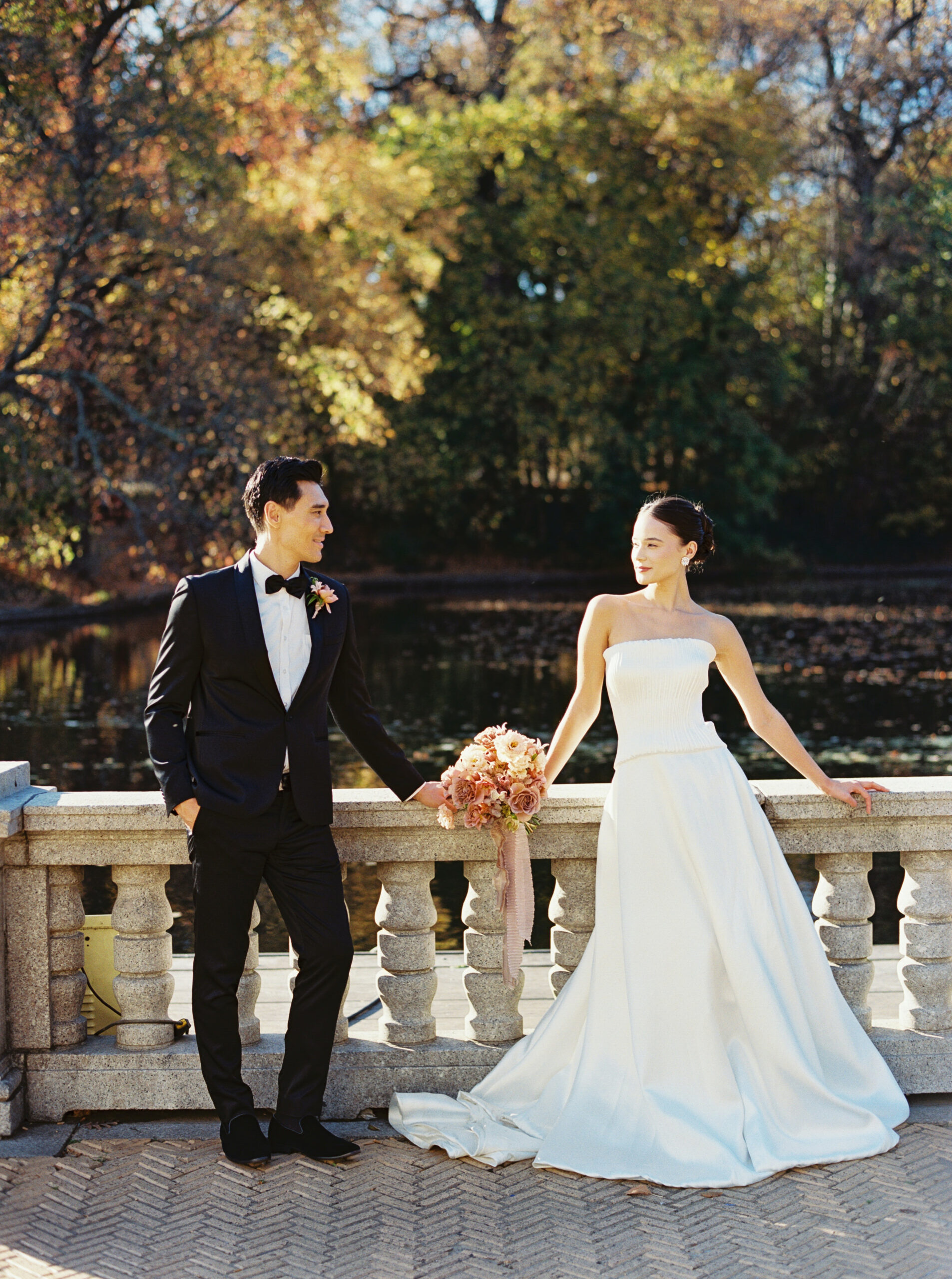 Bride and groom standing by the water at Purslane at the Boathouse in Prospect Park during fall, captured by Lexie Vaccaro Photography