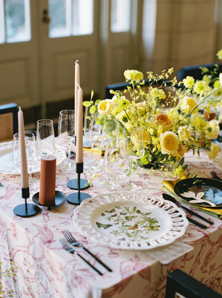 Wedding table with yellow floral centerpiece, butterfly motif plate, glassware, and taper candles
