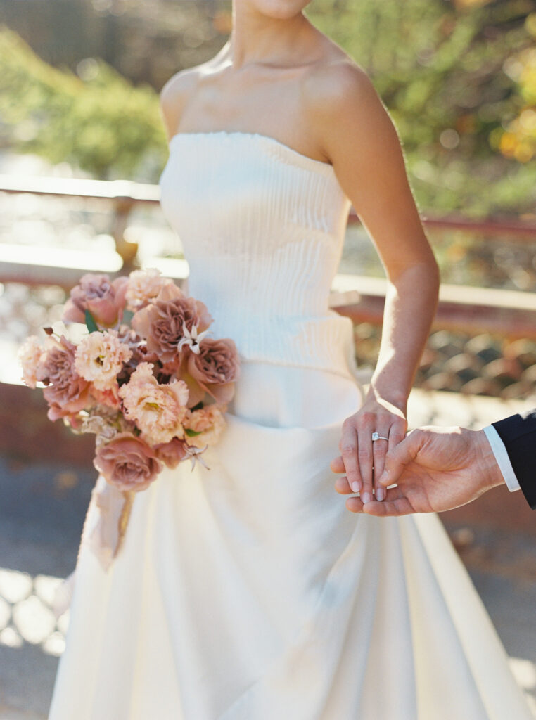 Bride in strapless gown holding groom’s hand and blush-toned bouquet, photographed at Prospect Park’s Boathouse