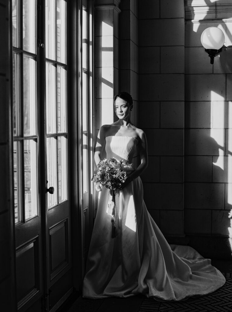 Bride holding bouquet in dramatic light and shadow inside Purslane at the Boathouse, photographed by Lexie Vaccaro Photography

