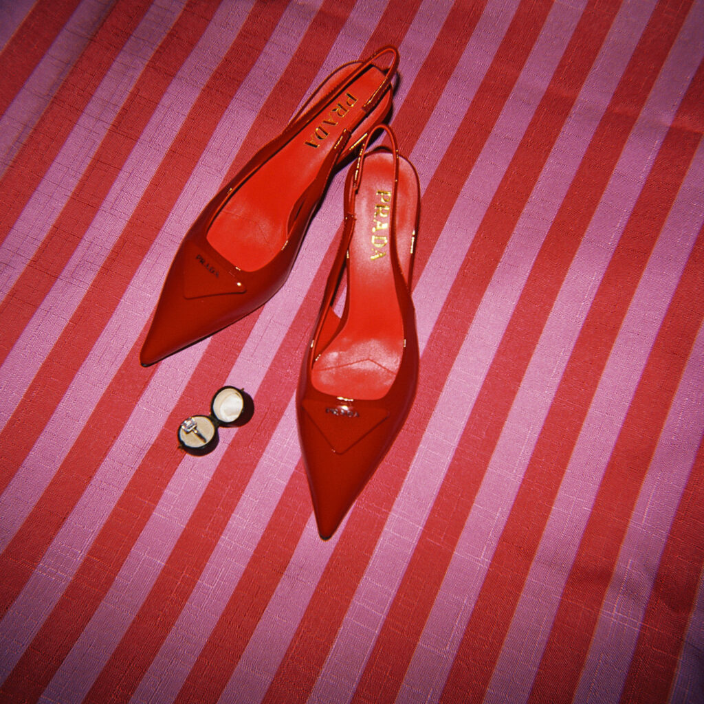Red Prada bridal heels with wedding ring on red and pink striped fabric, captured by Lexie Vaccaro Photography in NYC