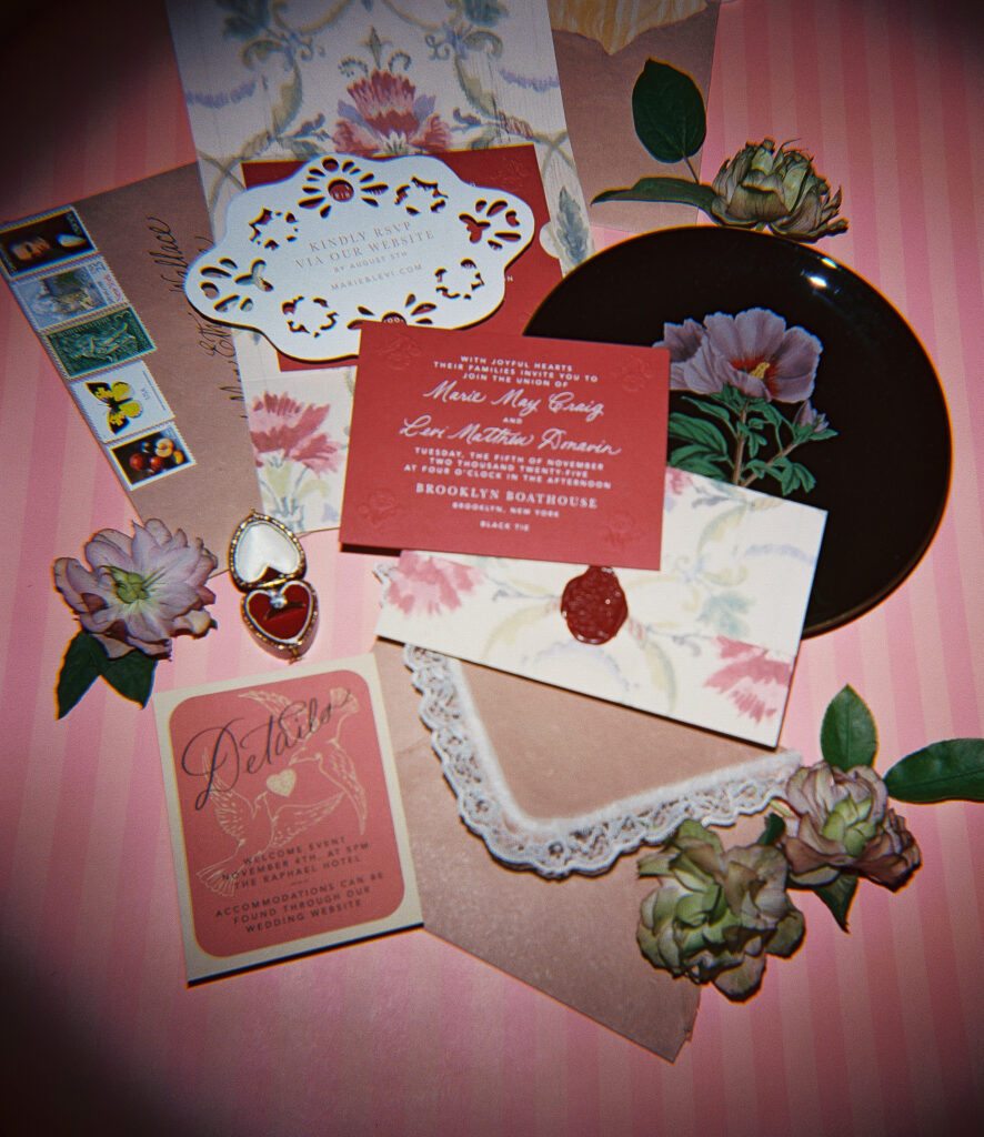 Flat lay of a romantic wedding invitation suite with floral details, lace, vintage stamps, and a wax seal, styled by Morgan Riley Design and photographed on film by Lexie Vaccaro Photography.