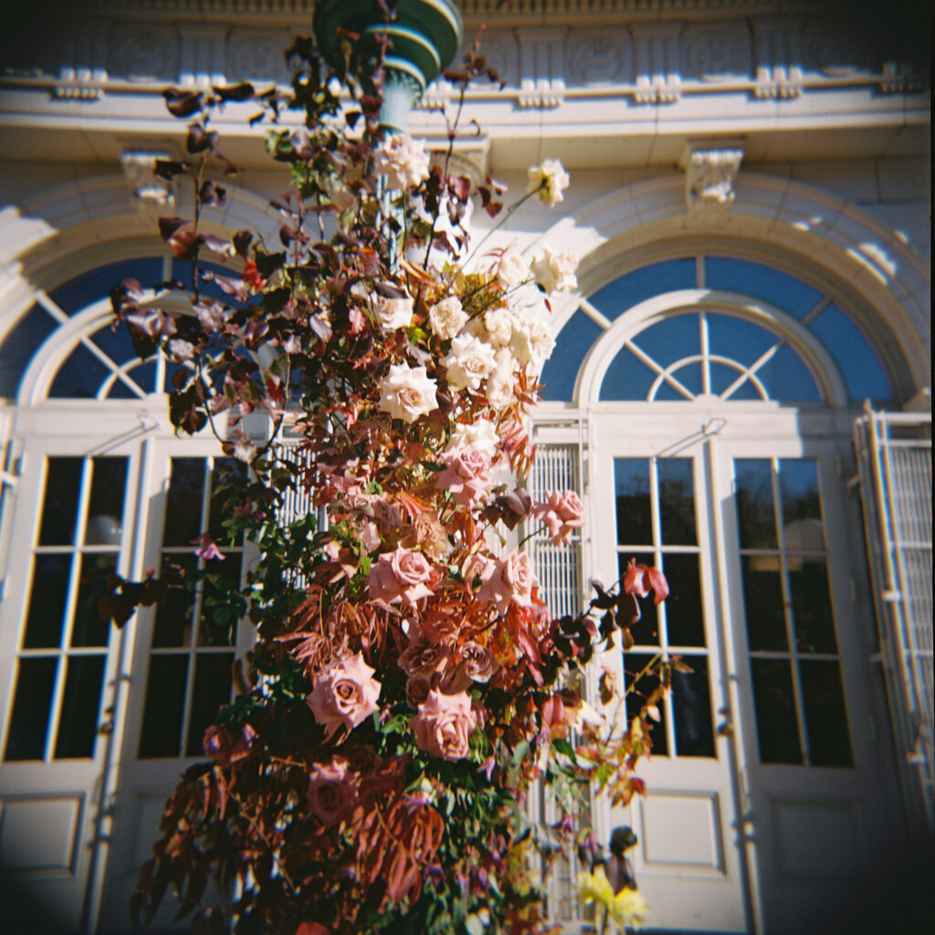 Romantic floral installation of blush and mauve roses on a vintage lamppost outside the Prospect Park Boathouse, captured on film.