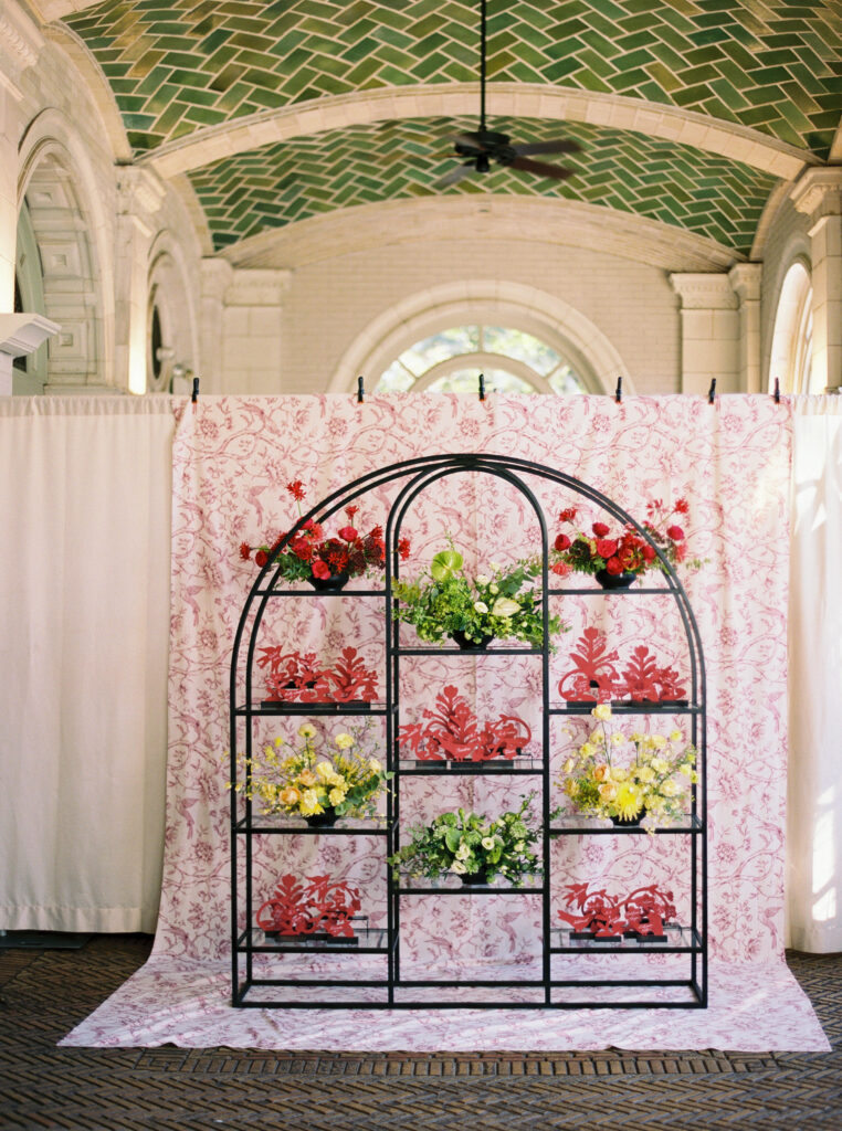 Intricate escort card display with floral arrangements and red origami at Purslane at the Boathouse in Prospect Park, styled by Britt Jones
