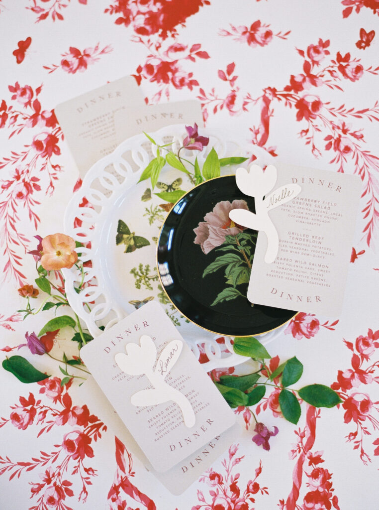 Flat lay of floral wedding table setting with vintage plates, custom menus, and butterfly illustrations, photographed on film by Lexie Vaccaro Photography